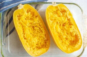 The contents of a clear glass baking dish, featuring two halves of squash spaghetti with shredded flesh inside, bring to mind the lush greens found in a Squash 'Spaghetti' 4" Pot.