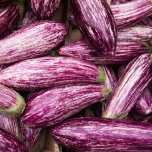 A bunch of Eggplant Striped 'Tsakoniki' in a 4" pot, with their purple and white striped skins nestled closely together, exudes a vibrant and fresh appeal.