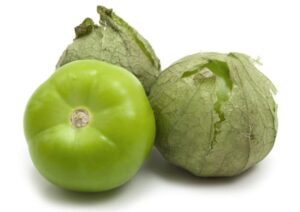 Three tomatillos, with two partially in husks, are set against a white background.