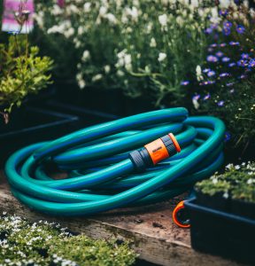 A Hose with Fittings and Tap Connectors 18mmx10m laying on a wooden bench.