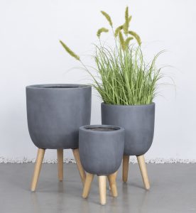 Three GardenLite Egg Planter with Legs Brushed Concrete (SET OF 3) are arranged together; one holds tall green grass, and two are empty.