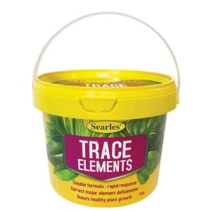 A yellow plastic tub labelled "Searles Trace Elements" with a white handle, used for correcting plant nutrient deficiencies and boosting growth.