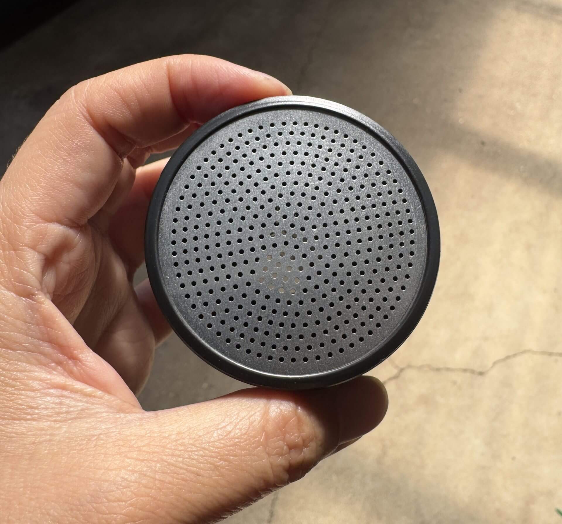 A hand holds the Hose Nozzle Water Breaker 400 Hole—black plastic head only—with a round, perforated front grille resembling its unique nozzle pattern.